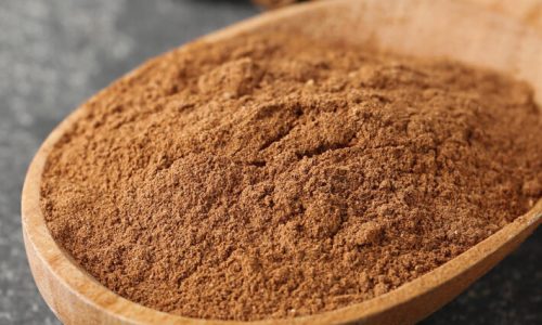 Aromatic cinnamon powder and sticks on grey table, closeup. Space for text